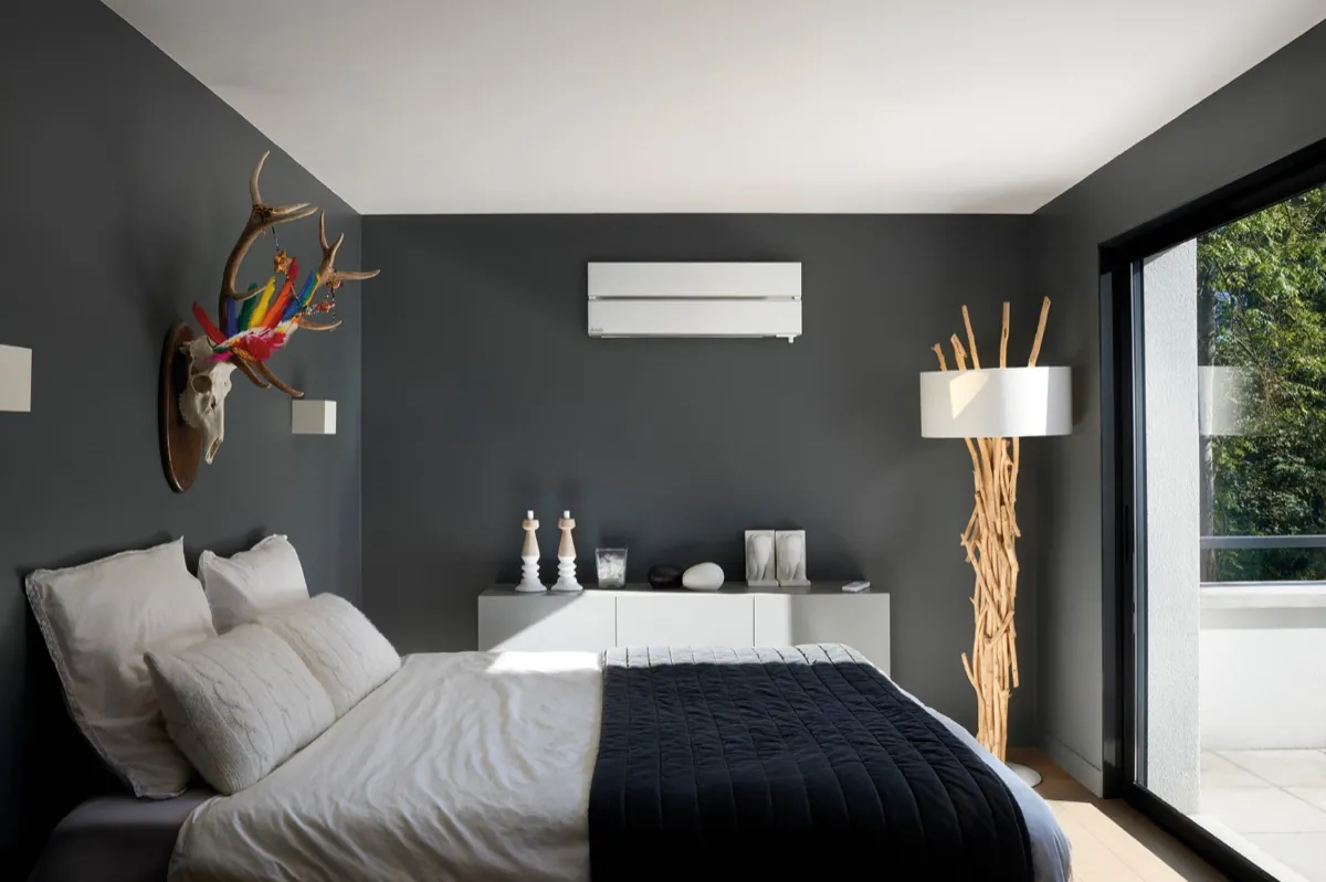 Slaapkamer met een witte wandairco naast een schuifpui